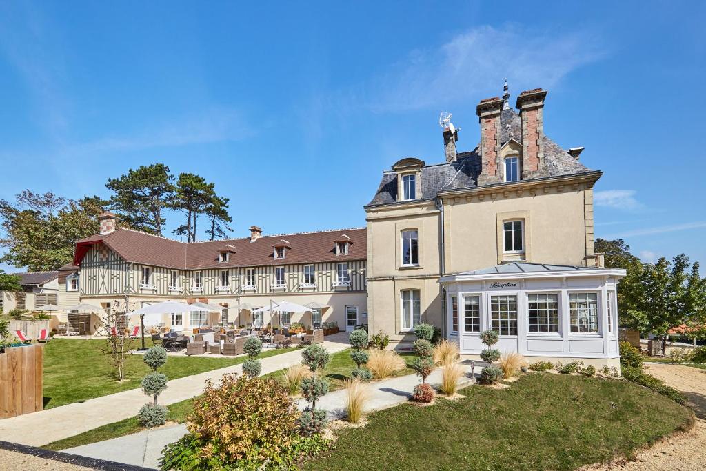 a large white house with a large window at Les Villas d'Arromanches, Les Collectionneurs in Arromanches-les-Bains