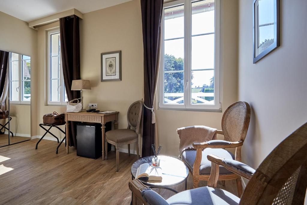 a living room with chairs and a desk and windows at Les Villas d'Arromanches, Teritoria in Arromanches-les-Bains