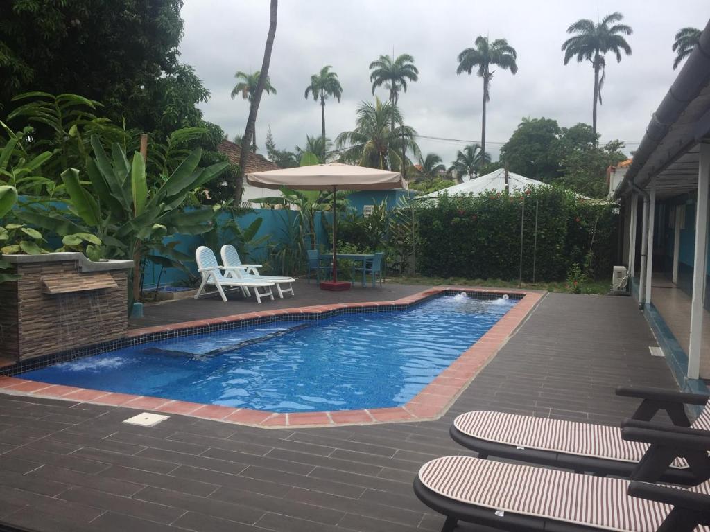 a swimming pool with chairs and an umbrella at Hotel Avenida in São Tomé