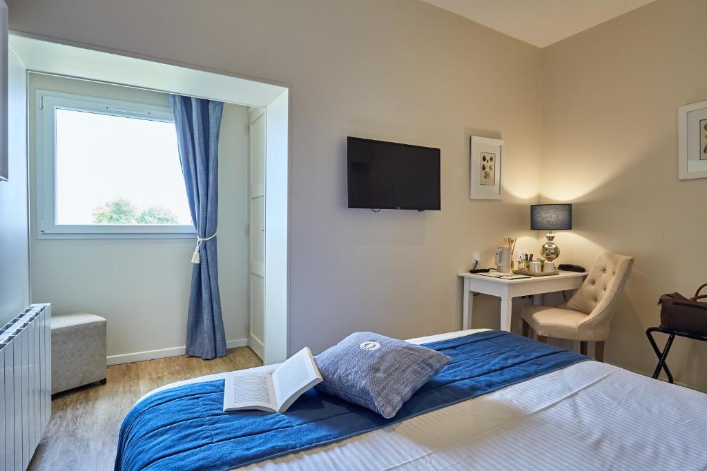 a bedroom with a bed and a window and a desk at Les Villas d'Arromanches, Teritoria in Arromanches-les-Bains