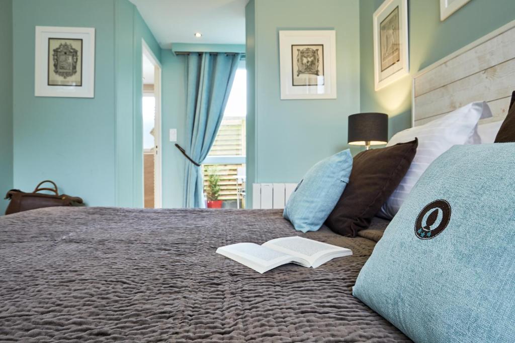 a bedroom with a bed with a book on it at Les Villas d'Arromanches, Teritoria in Arromanches-les-Bains