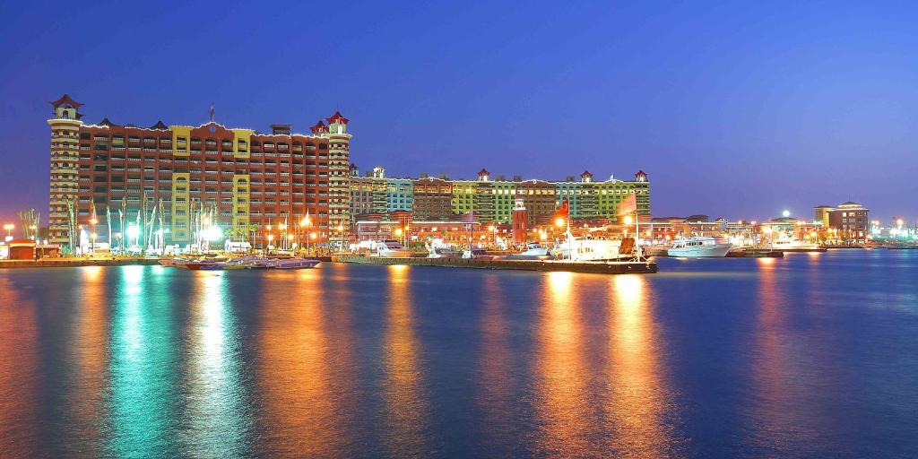 uma vista para um hotel e uma cidade à noite em Porto Marina Apartments By Amer-Group em El Alamein