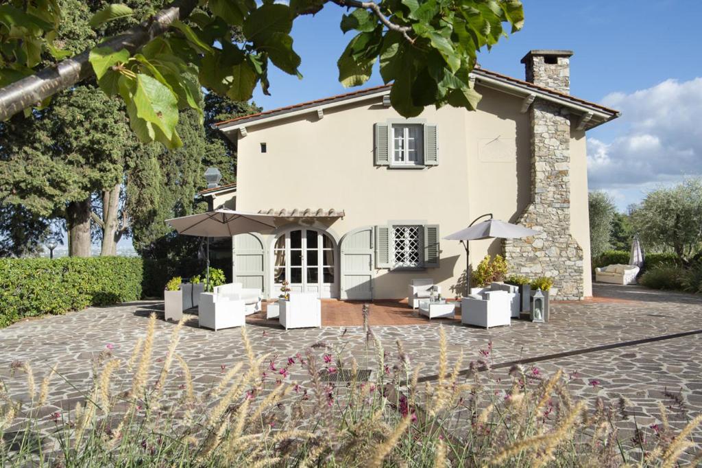 een patio voor een huis met parasols bij Villa Zelma in Cantagrillo