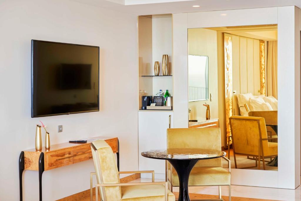 a living room with a table and chairs and a television at Savoy Palace - The Leading Hotels of the World - Savoy Signature in Funchal