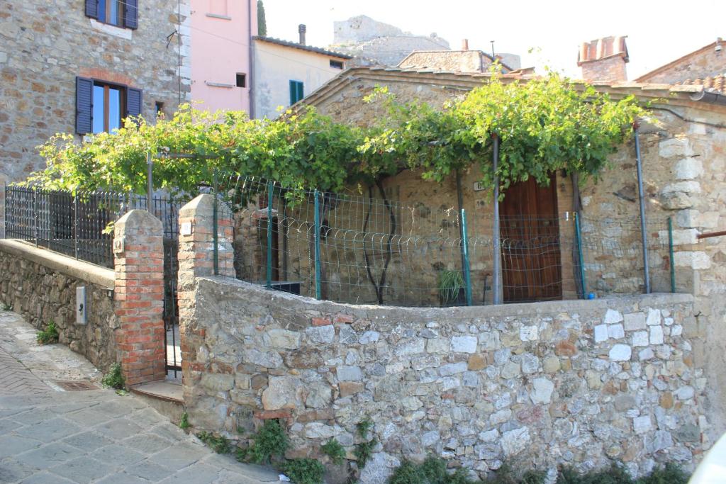 a stone wall with a fence with plants on it at La Casina di Nonna Lola in Castiglione dʼOrcia