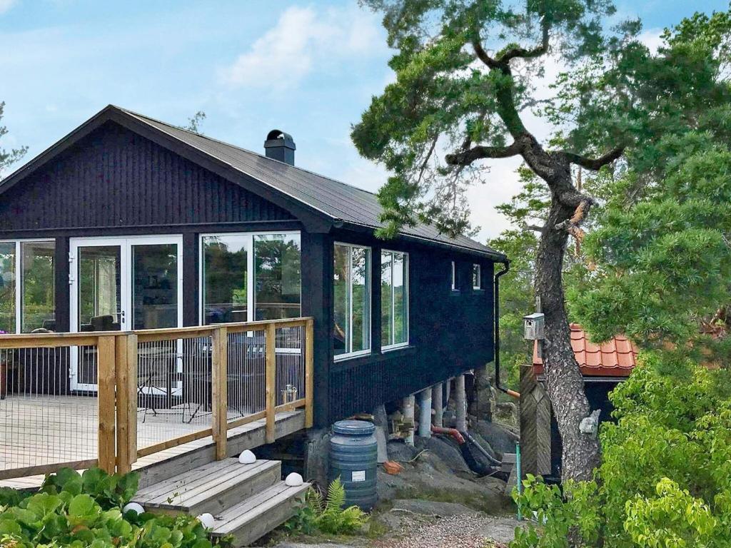 ein schwarzes Haus mit einer Veranda und einem Baum in der Unterkunft 4 person holiday home in KERSBERGA in Åkersberga