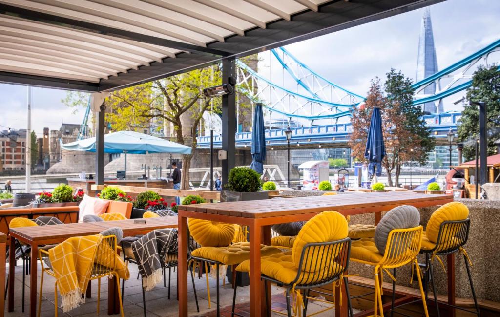 a patio with tables and chairs and a view of the city at The Tower Hotel, by Thistle in London