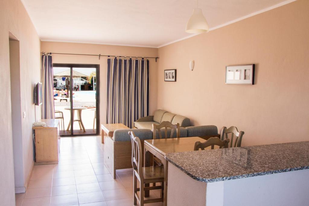 a living room with a couch and a table with chairs at Apartamentos Lanzarote Paradise Colinas in Costa Teguise