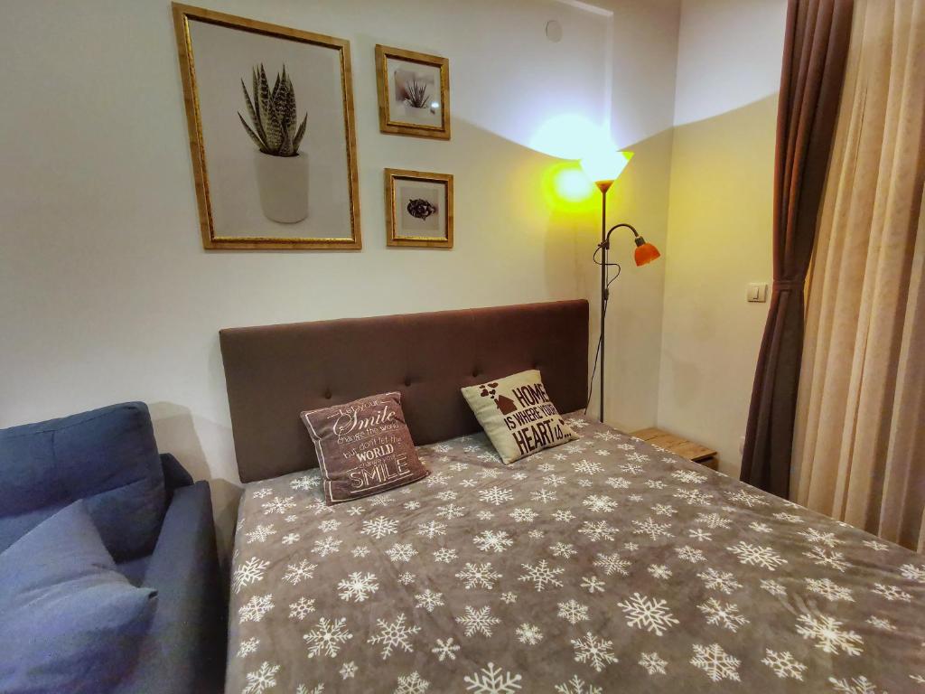 a bedroom with a bed and a blue couch at Apartman Pahulja - Milmari in Kopaonik