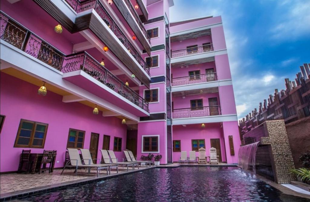 a pink building with a swimming pool in front of it at Changpuak Boutique House in Chiang Mai
