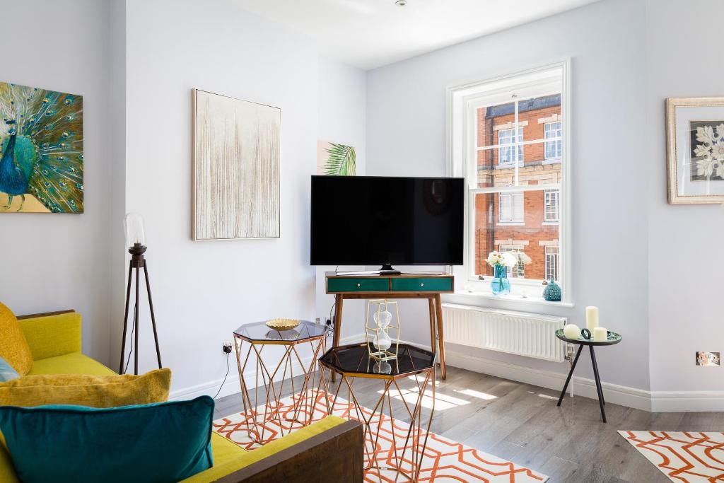 - un salon avec une télévision et un canapé dans l'établissement 24 Molyneux Street, à Londres