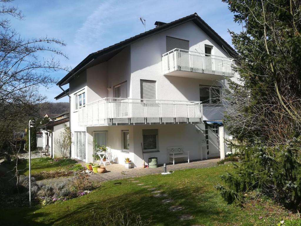 a white house with a balcony and a yard at Ferienwohnung Madeleine in Donzdorf