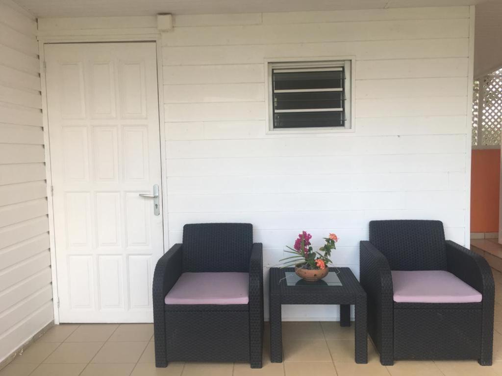 two chairs and a table in front of a door at La perle créole in Lamentin