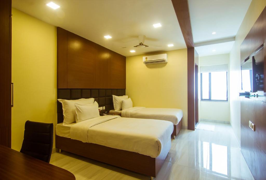a hotel room with two beds and a table at Hotel Sawood International in Kolkata