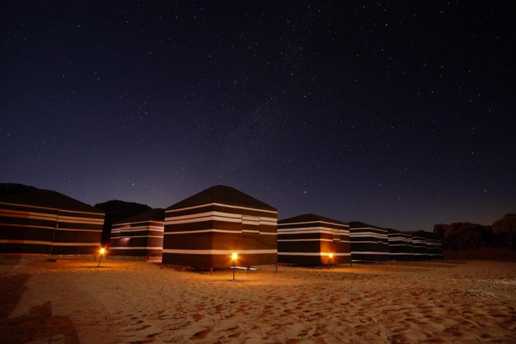 Una fila de edificios en el desierto por la noche en Star City Camp wadirum, en Wadi Rum