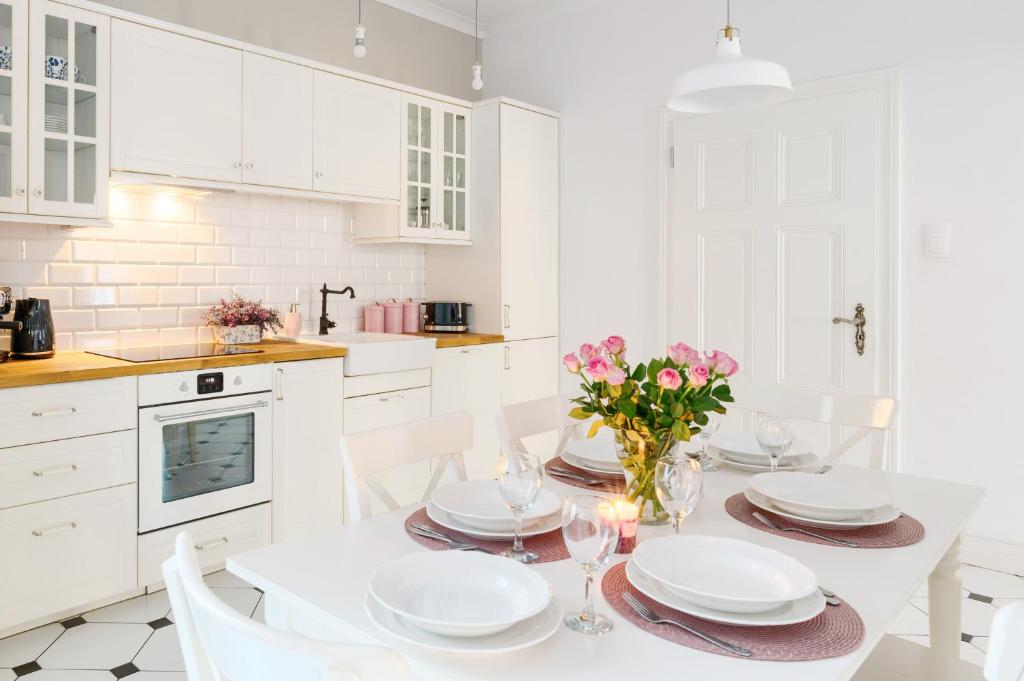 een witte keuken met een eettafel en stoelen bij Apartament Nowe Miasto - przy Parku Róż in Gorzów Wielkopolski