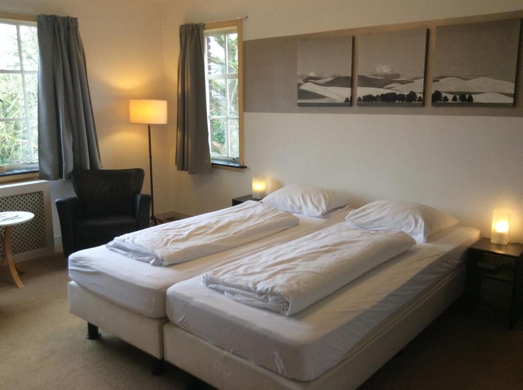 een hotelkamer met 2 bedden en een stoel bij BergOpwaerts in Sint Odiliënberg