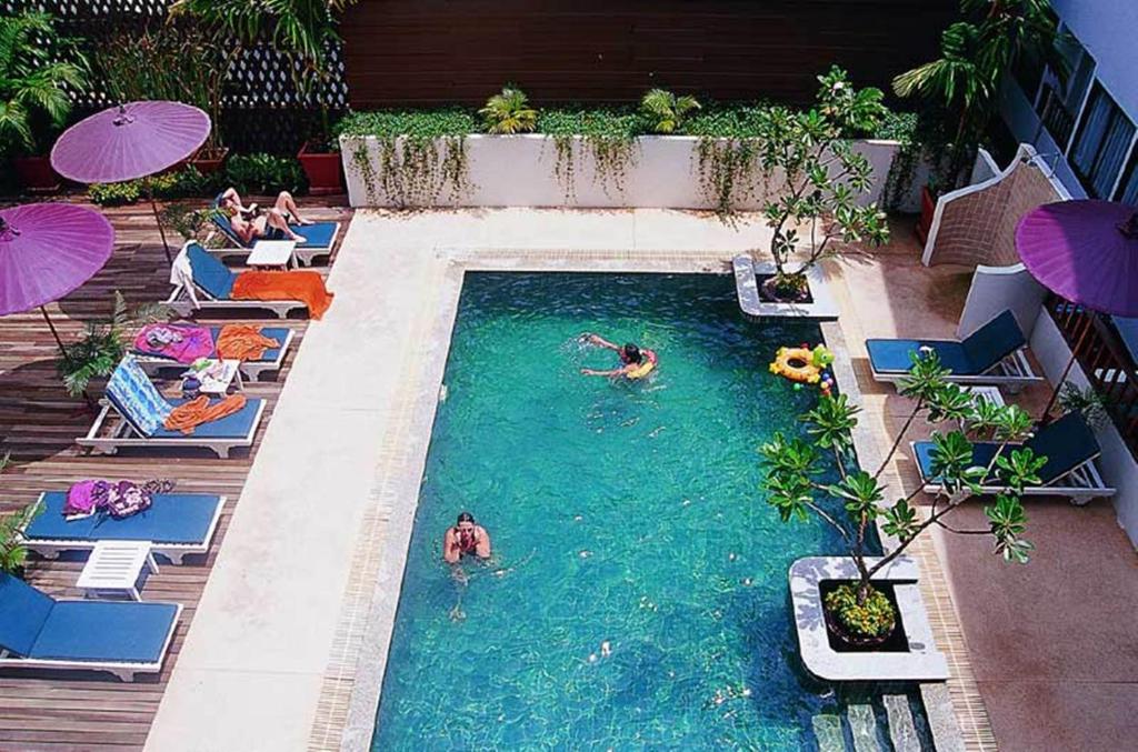 a swimming pool with people in the water at BP Chiangmai City Hotel in Chiang Mai