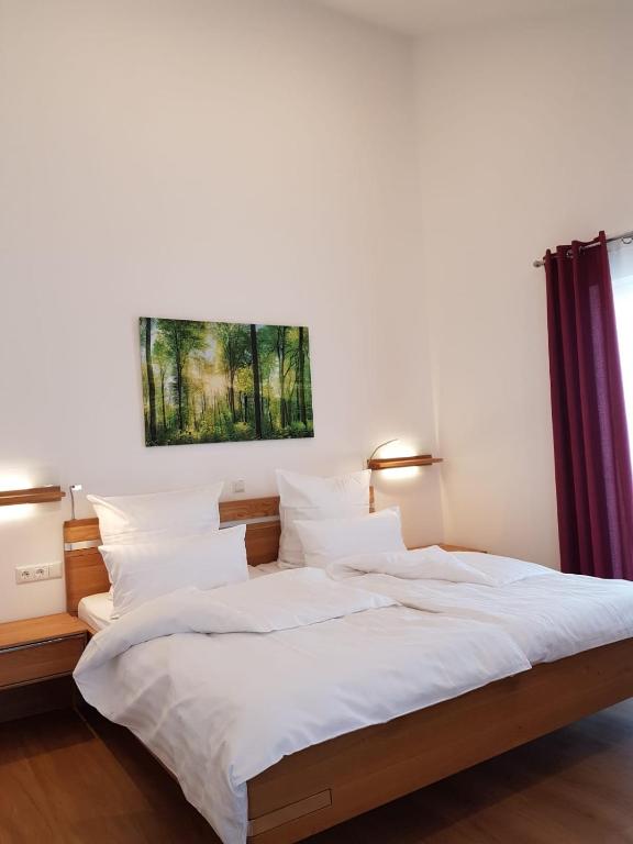 a bedroom with a large bed with white sheets and pillows at Gästehaus Staudenschloss in Mickhausen