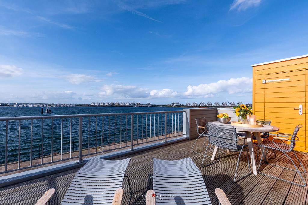 a balcony with a table and chairs and the ocean at Ferienwohnung Hafenkieker in Olpenitz