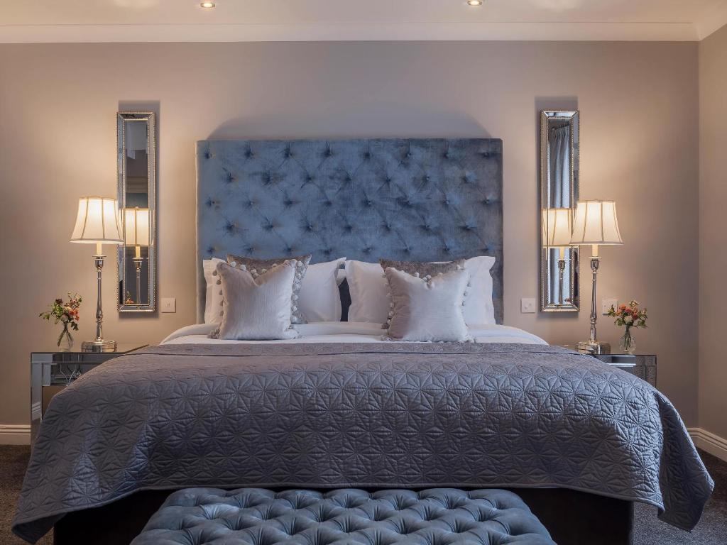 a bedroom with a large bed with a blue headboard at The Ashe Hotel in Tralee