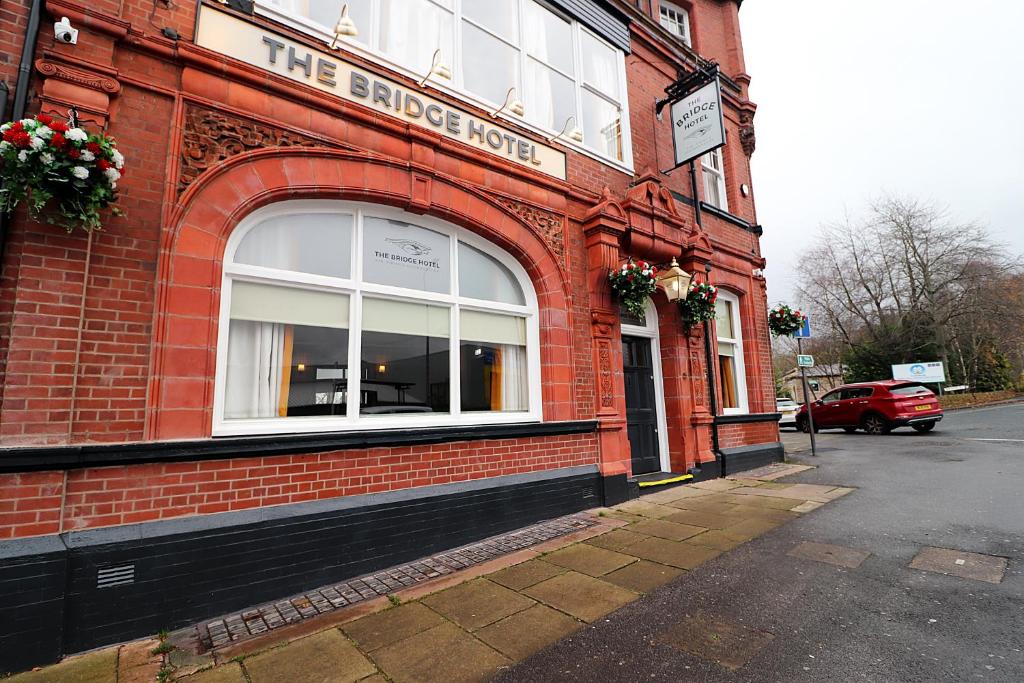 un edificio de ladrillo rojo con un cartel en el costado en The Bridge Inn Hotel en Bolton