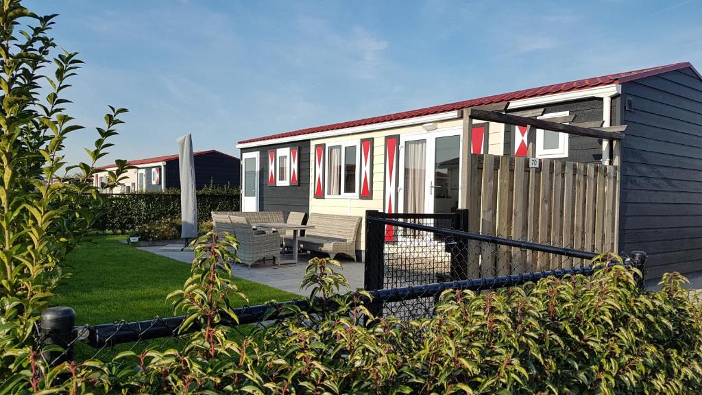 ein kleines Haus mit Picknicktisch und Zaun in der Unterkunft Chalet Veere - eingezäunter Garten, hundefreundlich & ruhig in Zeeland in Serooskerke