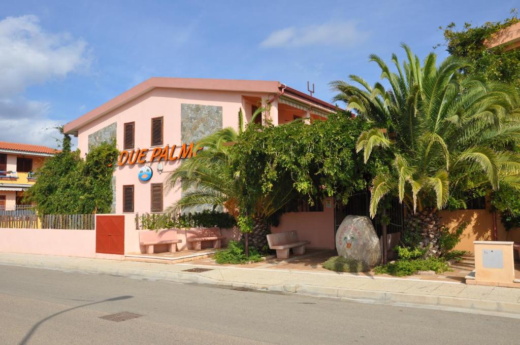 un edificio al lado de una calle con palmeras en Residenza Le Due Palme en Villasimius