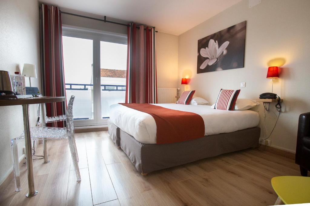 Hotel Epi d'Or في أنغوليم: غرفة فندقية بسرير ونافذة كبيرة