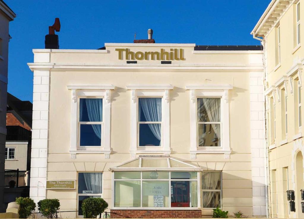 un bâtiment blanc avec un panneau tumulus sur celui-ci dans l'établissement The Thornhill, à Teignmouth