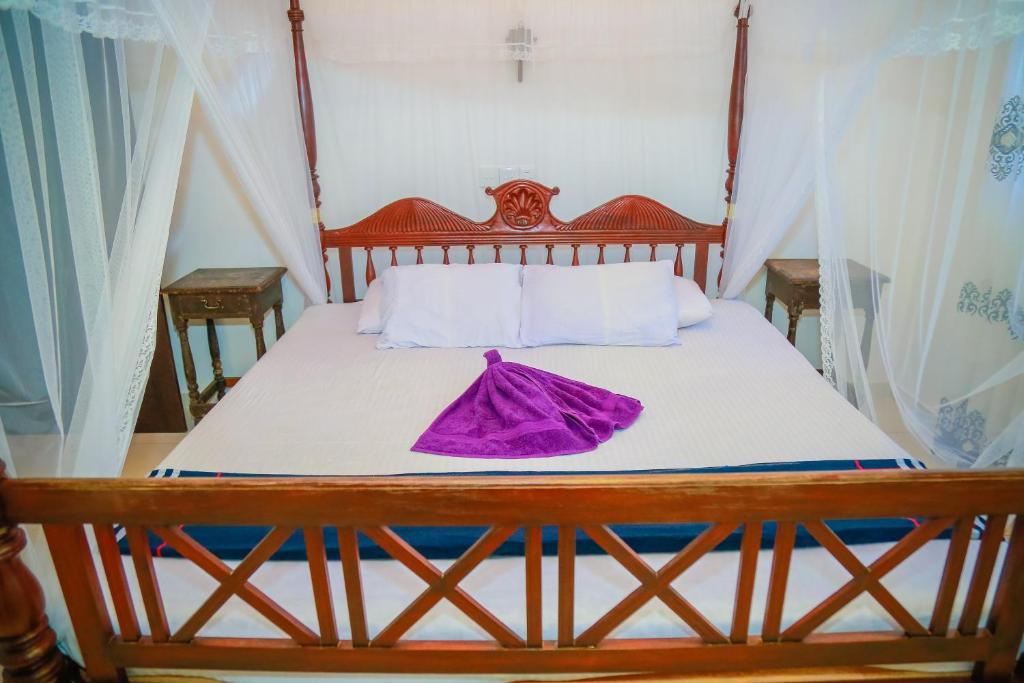 a bed with a wooden headboard with a purple dress on it at VILLA No34 HIKKADUWA in Hikkaduwa