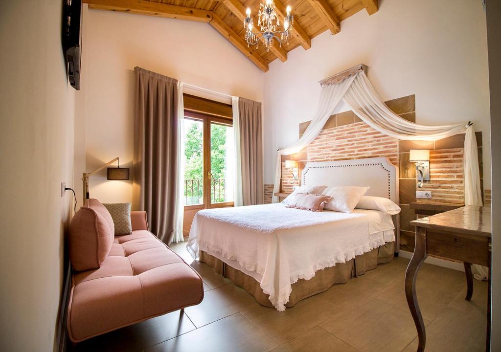 a bedroom with a bed and a chair and a window at El Patio de la Morera in El Rasillo