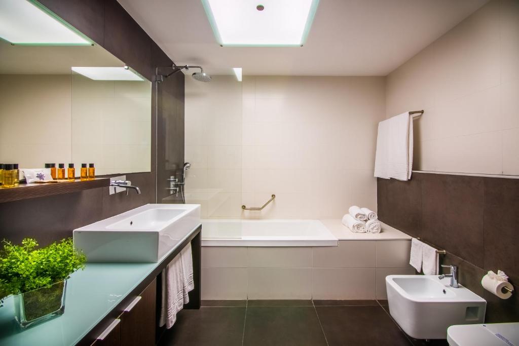 a bathroom with a sink and a tub and a toilet at RR Hotel da Rocha in Portimão