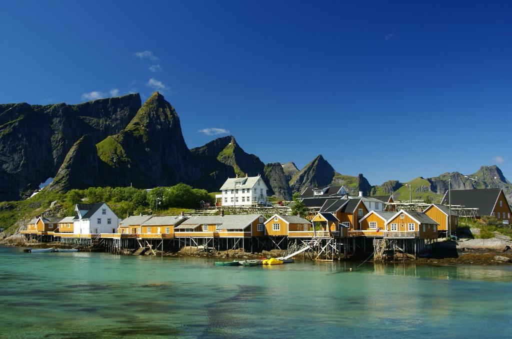 un villaggio sull'acqua con montagne sullo sfondo di Sakrisøy Rorbuer a Reine