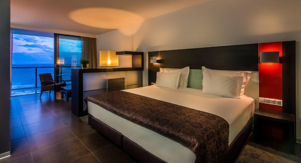 a hotel room with a bed with a view of the ocean at RR Hotel da Rocha in Portimão