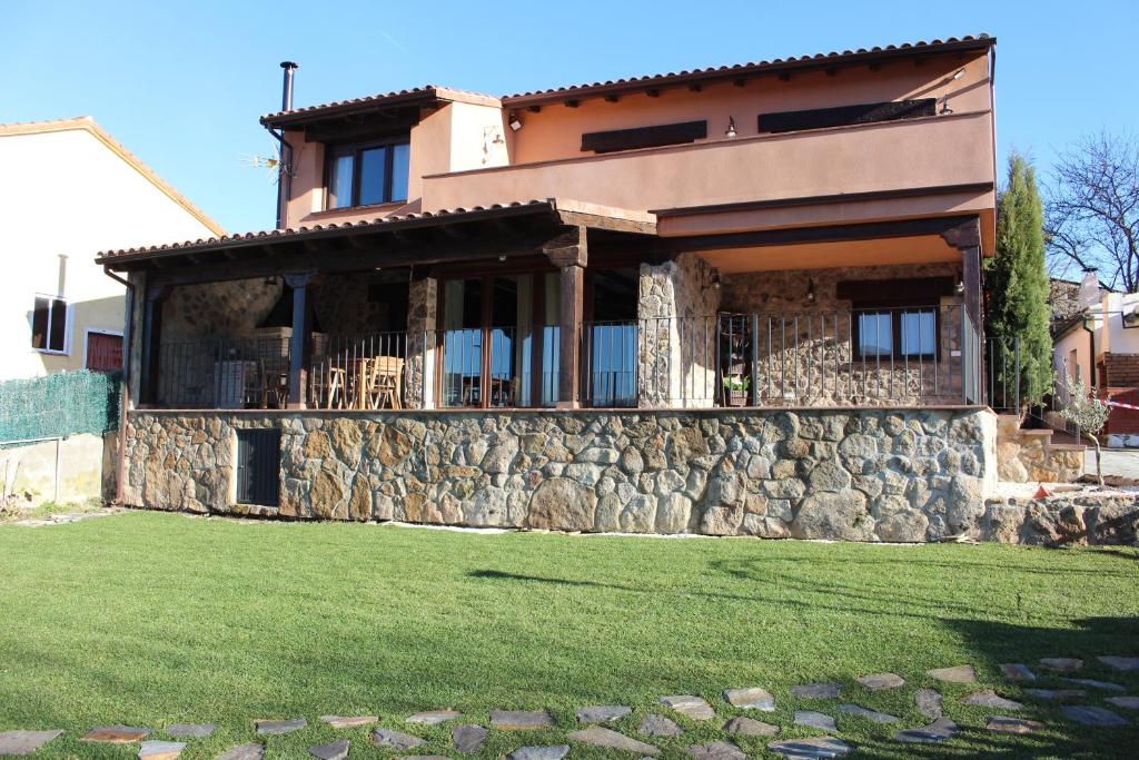 a house with a stone wall and a yard at Casa Rural Los 3 Panetes in Peñacaballera