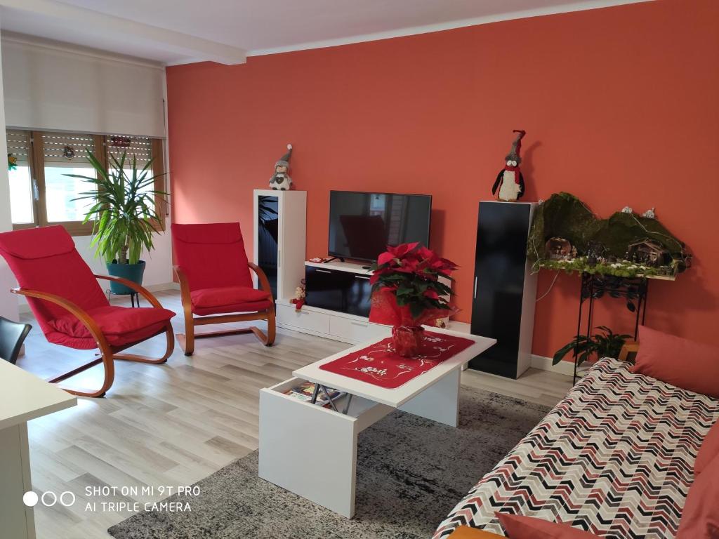 a living room with red chairs and a tv at Apartamento confort I in La Seu d'Urgell