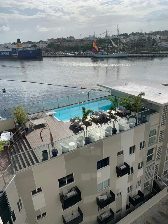 a building with a swimming pool next to a body of water at Mirador Colonial, en Riviera Colonial in Santo Domingo