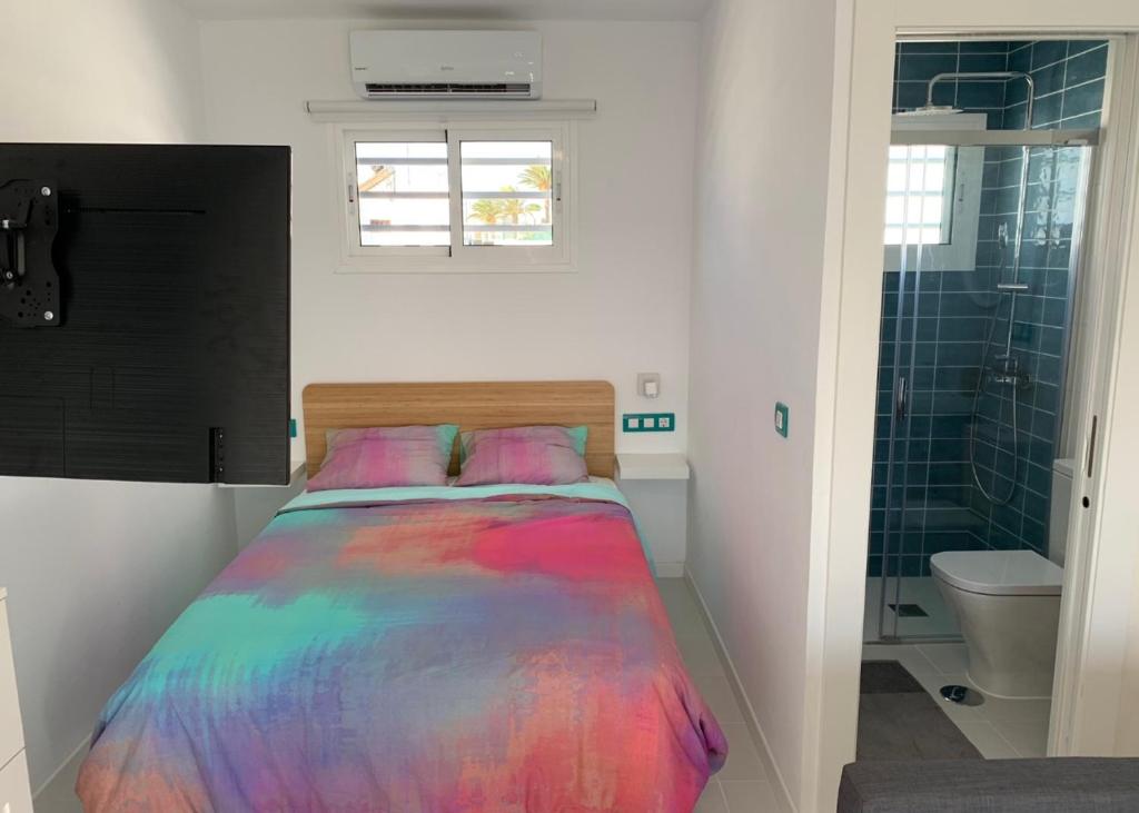 a bedroom with a colorful bed and a bathroom at Puerto del Carmen Luxury Apartment in Tías