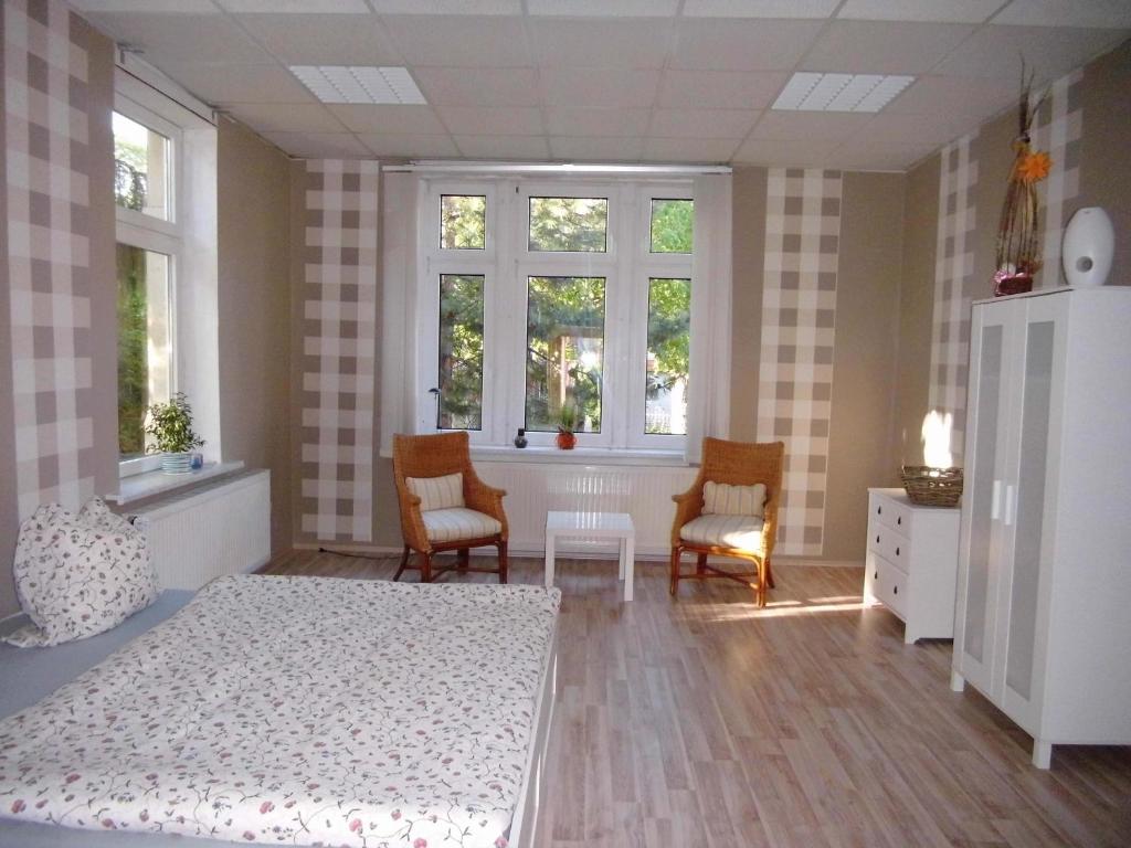 a bedroom with a bed and two chairs and windows at Ferienwohnung Markert in Blankenburg