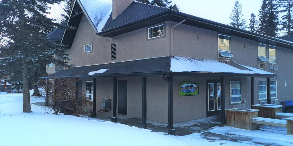 a building with snow on the ground in front of it at Mountain View Inn in Canmore