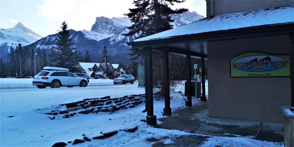 a snow covered street with cars parked next to a building at Mountain View Inn in Canmore