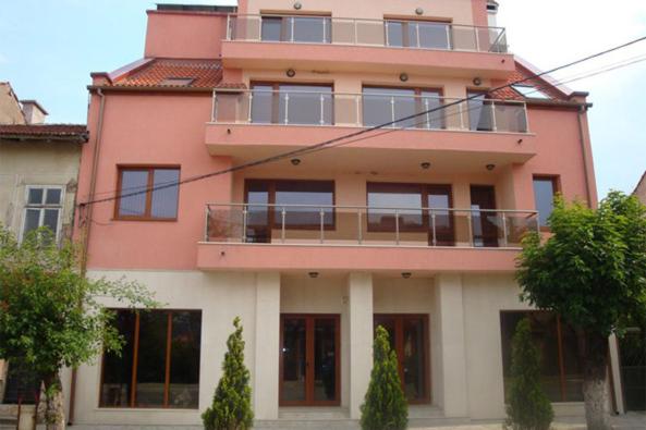 un bâtiment rose avec un balcon en haut. dans l'établissement Tzvetelina Palace Hotel, à Dolna Banya