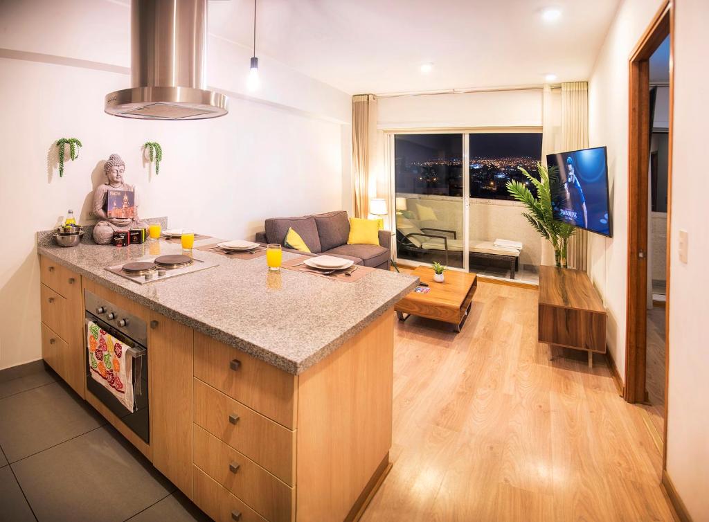 a kitchen with a counter and a living room at Resort Style Condo near heart of AQP - Gym, Pool & Netflix in Arequipa