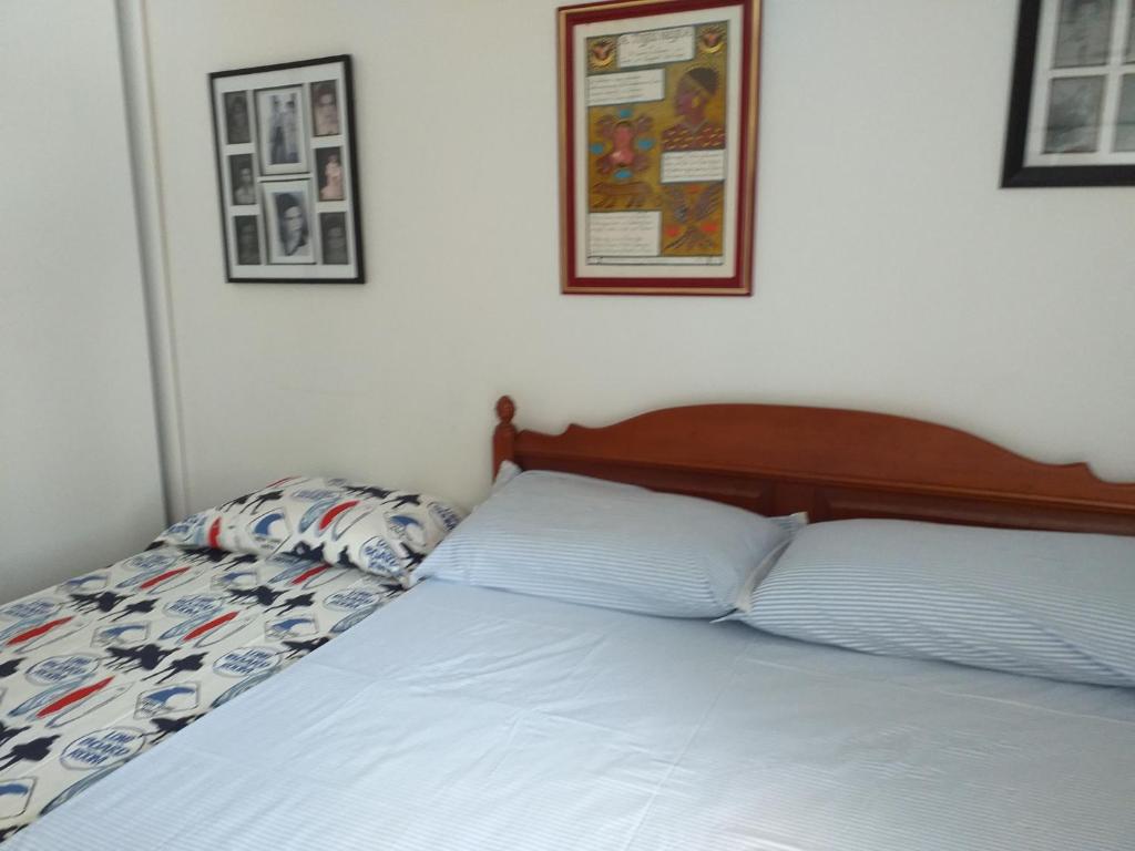 a bed in a bedroom with two pictures on the wall at AMPLA e CONFORTÁVEL SUITE - PERTO DO CENTRO DE CONVENÇÕES-FENEARTE-FEIRAS-CONGRESSOS-SHOWs-RECIFE in Recife