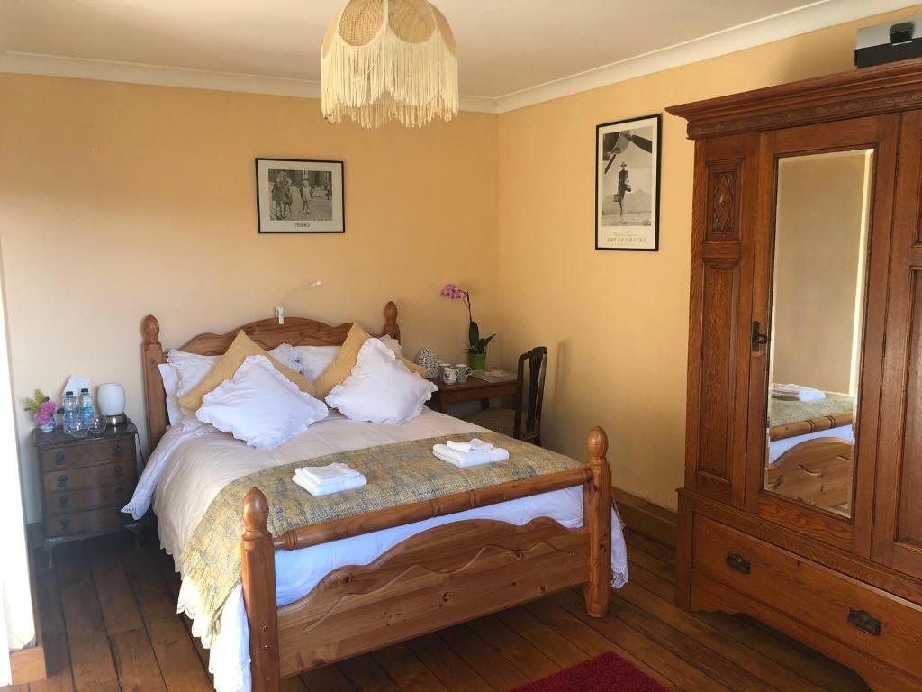 a bedroom with a bed with a table and a mirror at Cilffriw Farm in Neath