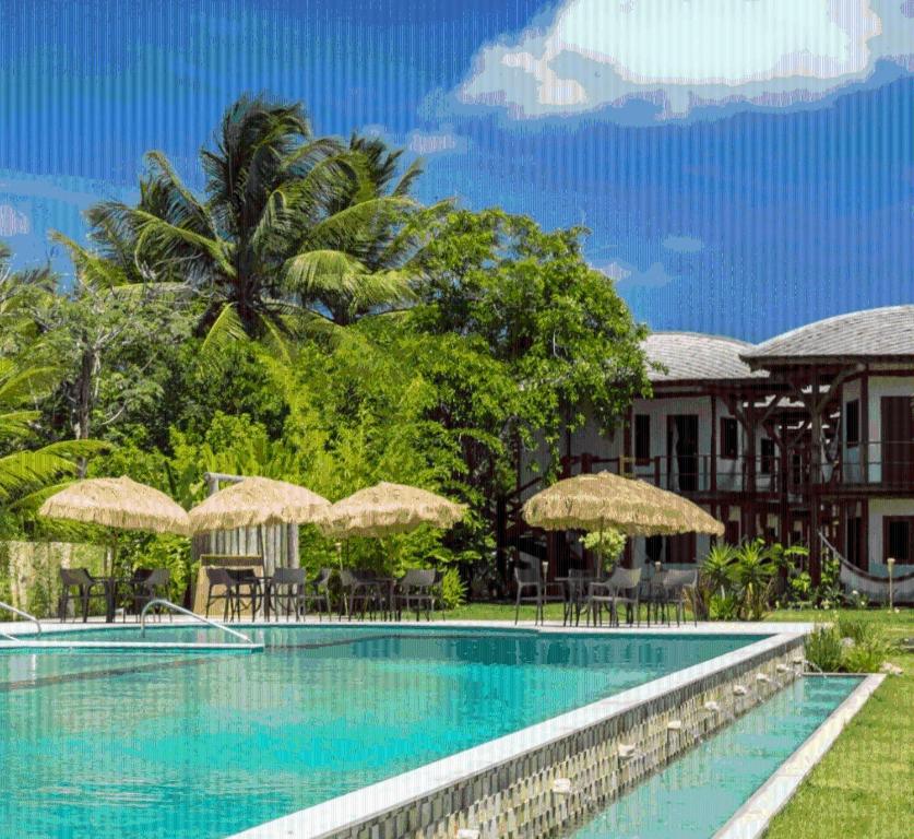 Hotel Villa Balidendê في بارا غراندي: مسبح المنتجع مع الكراسي والمظلات
