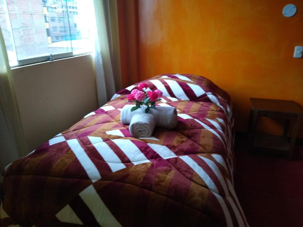a bed with flowers and towels on it at Hostal Lucky Puno in Puno