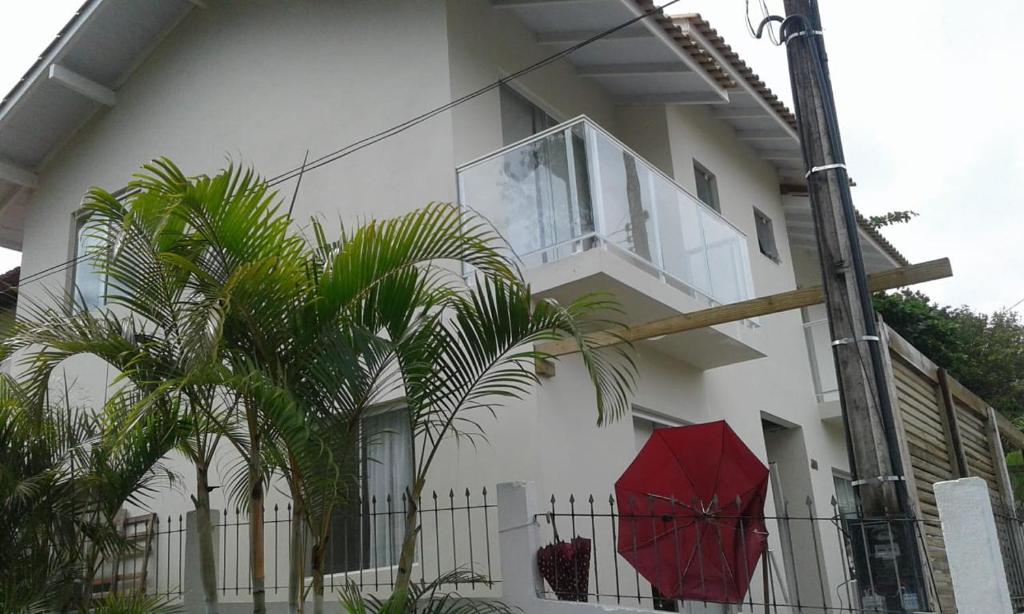una casa blanca con un paraguas rojo delante de ella en Moradas Lagoinha, en Florianópolis