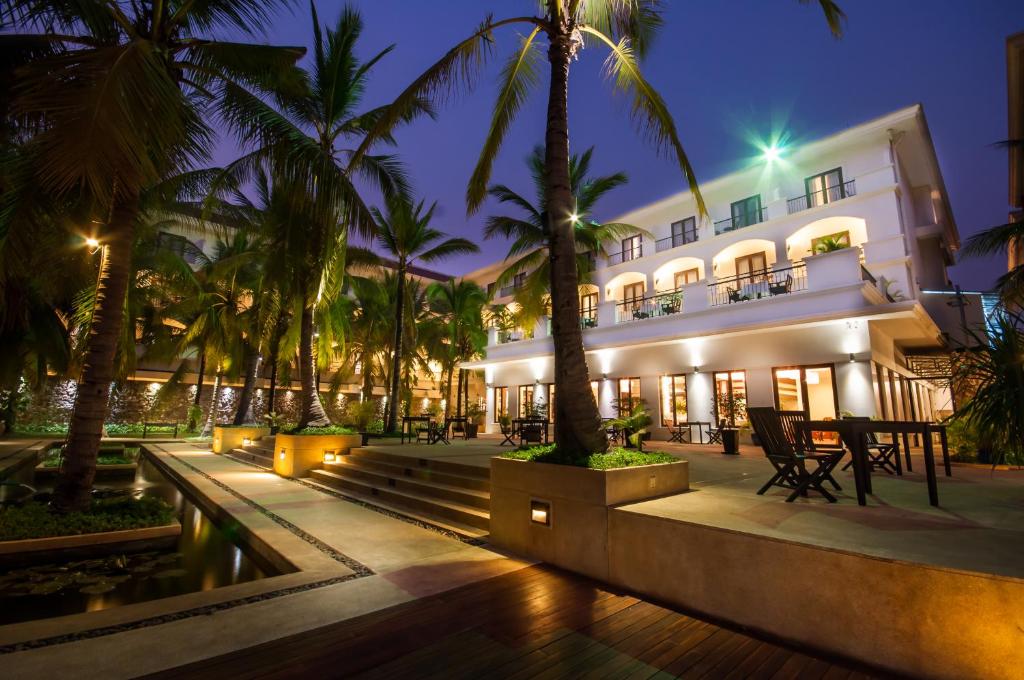 a hotel with palm trees in front of a building at Lotus Blanc Resort in Siem Reap